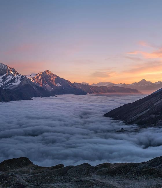 Bergkette über einem Wolkenmeer im Abendlicht