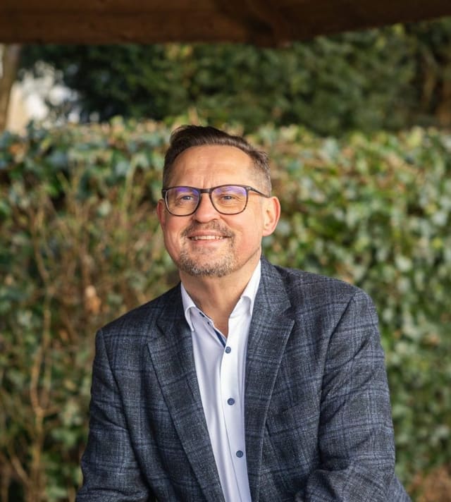 Peter Budniak, weltlicher Trauerredner, im Freien vor einer Hecke